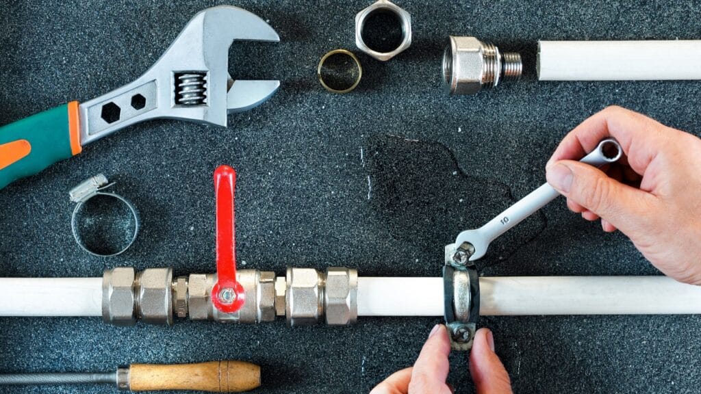 Plumber repairing a pipe valve with an adjustable wrench in Naples