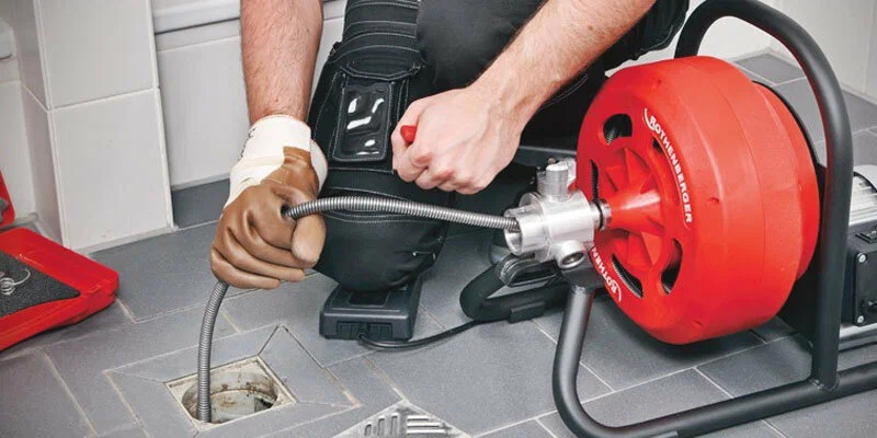 Plumber using a drain-cleaning machine in Naples