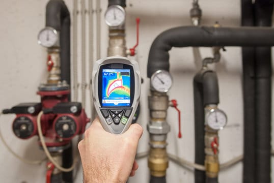 Plumber using a thermal imaging camera to inspect pipes in Naples