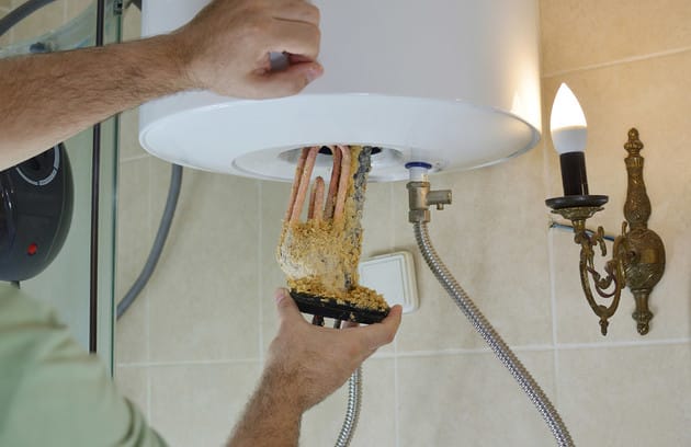 Technician removing mineral buildup from a water heater in Naples