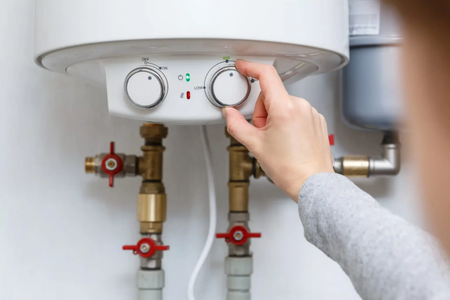 Homeowner adjusting the temperature controls on a water heater in Naples